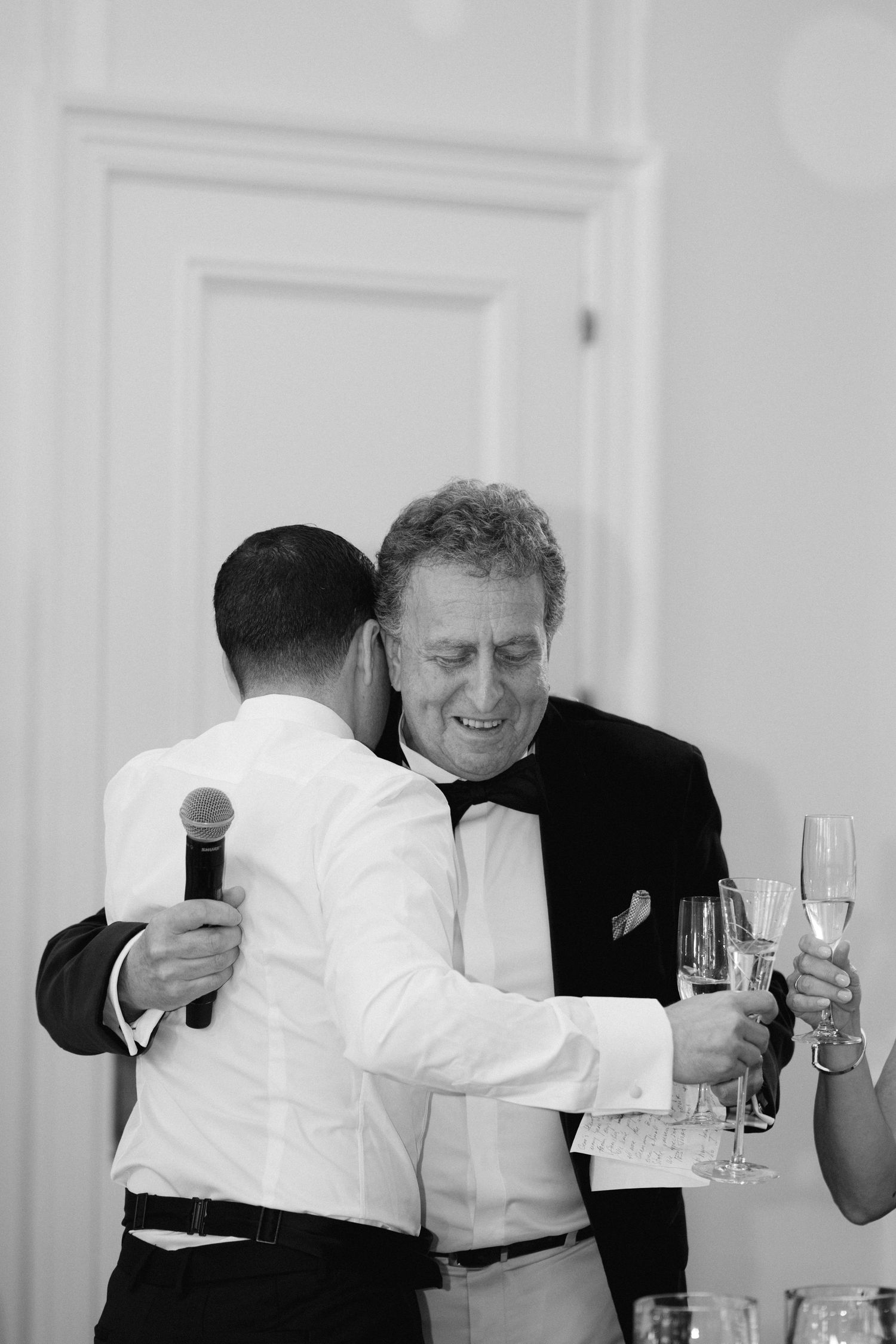 Two people in formal attire share an emotional moment while holding champagne glasses at an elegant event.
