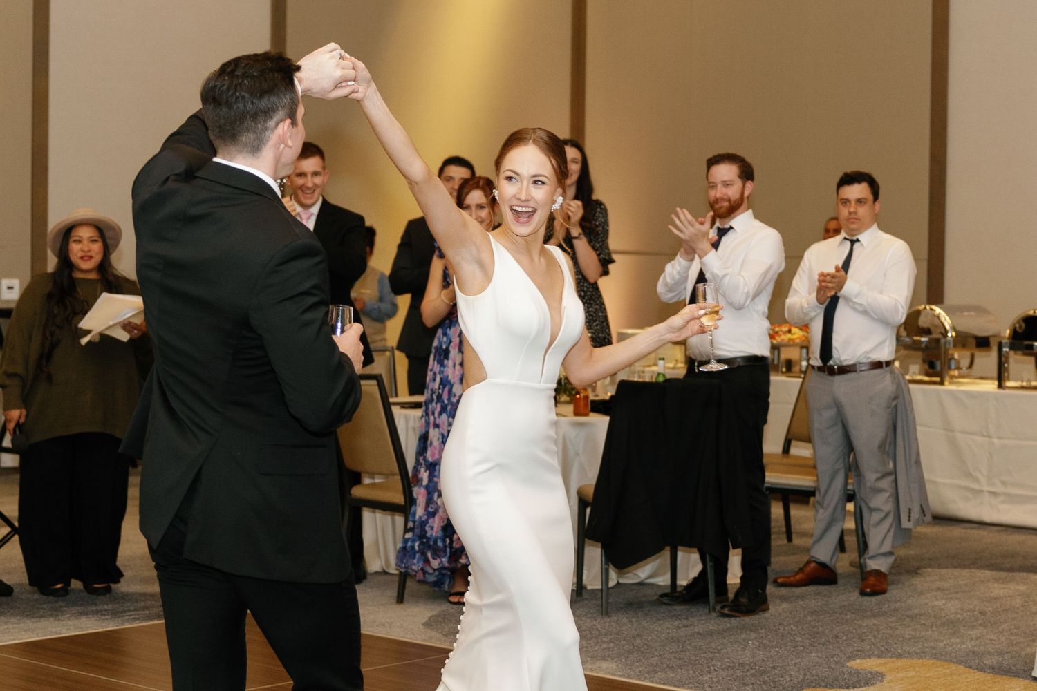 Newlyweds dance together at their wedding reception while guests watch and celebrate from the sidelines.