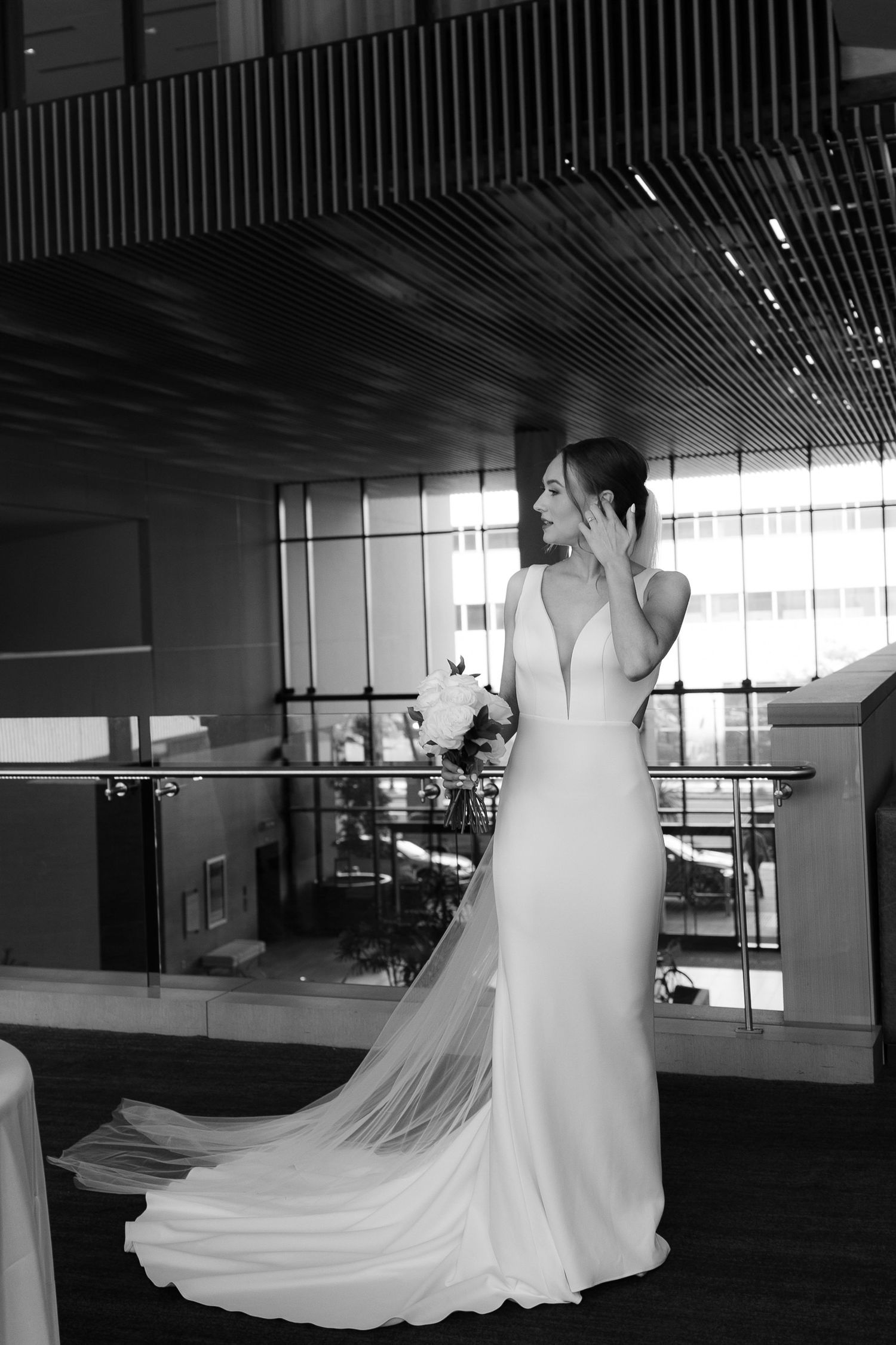 A flowing white wedding dress with a long train twirls gracefully in a series of connected photos in an indoor space.