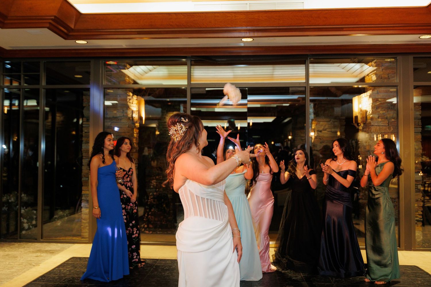 Wedding party dances together on a dimly lit dance floor during an evening reception celebration.