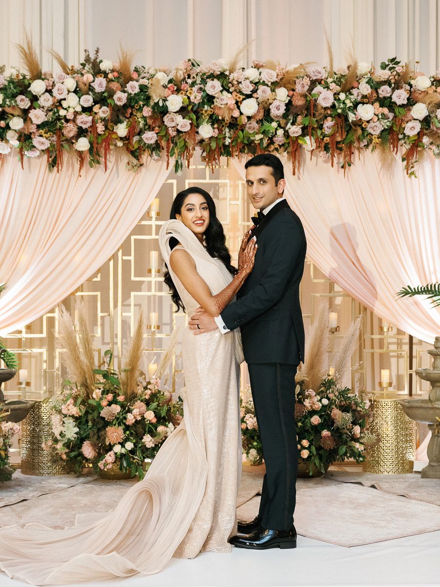 Elegant wedding ceremony setup with white drapes and floral arch decorations in peach and blush tones.