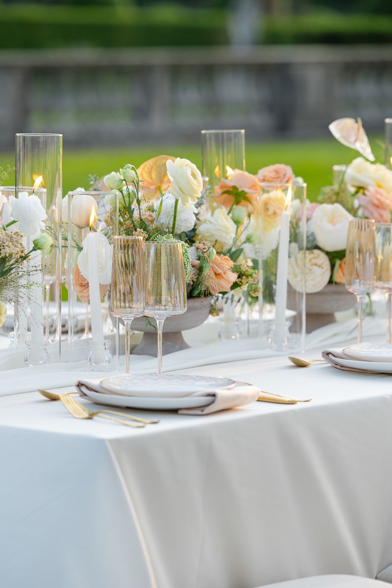 Elegant wedding reception table setting with white linens, delicate floral centerpieces and crystal glassware.