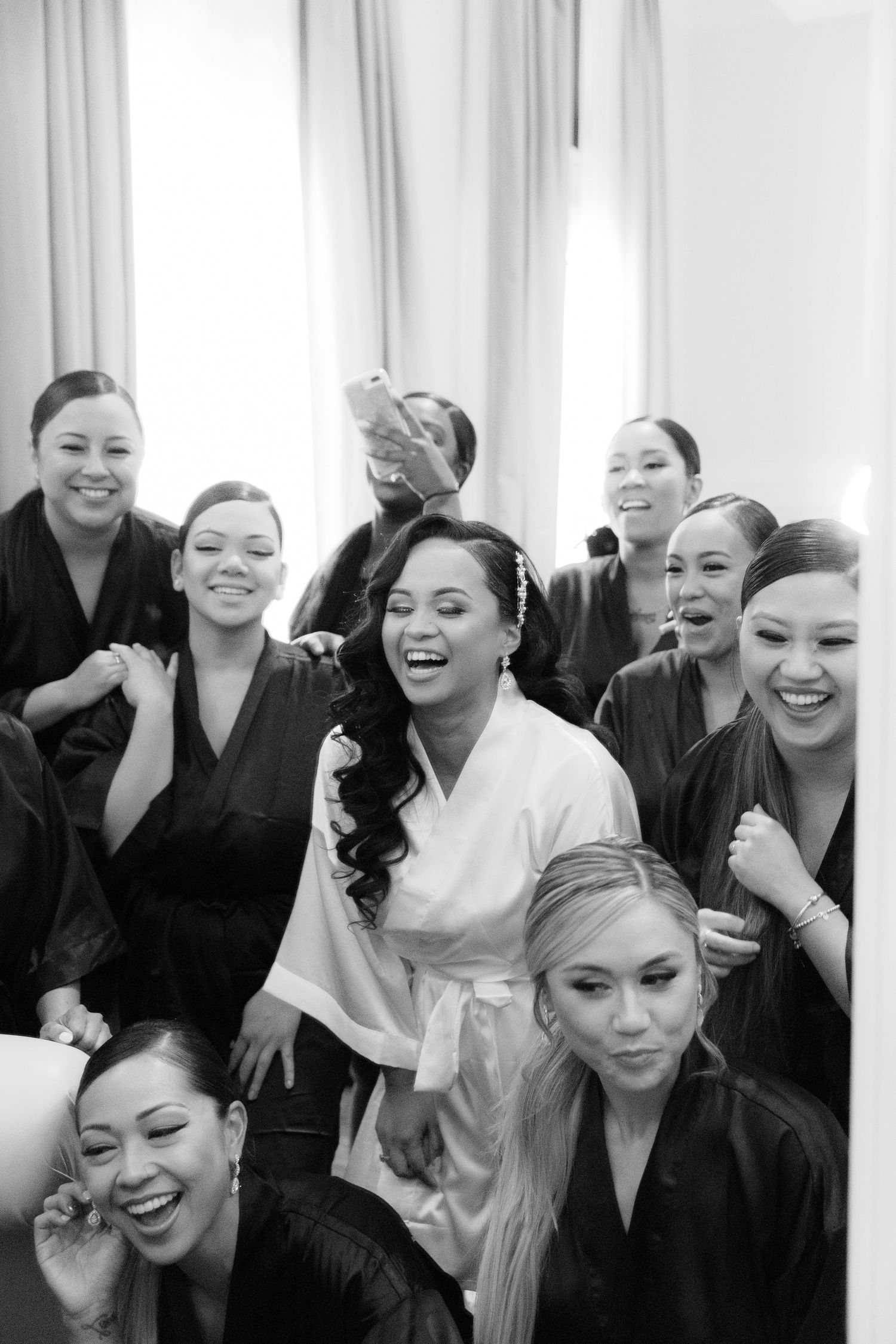 A sequence of four black and white photos showing a group of bridesmaids getting ready and laughing together.