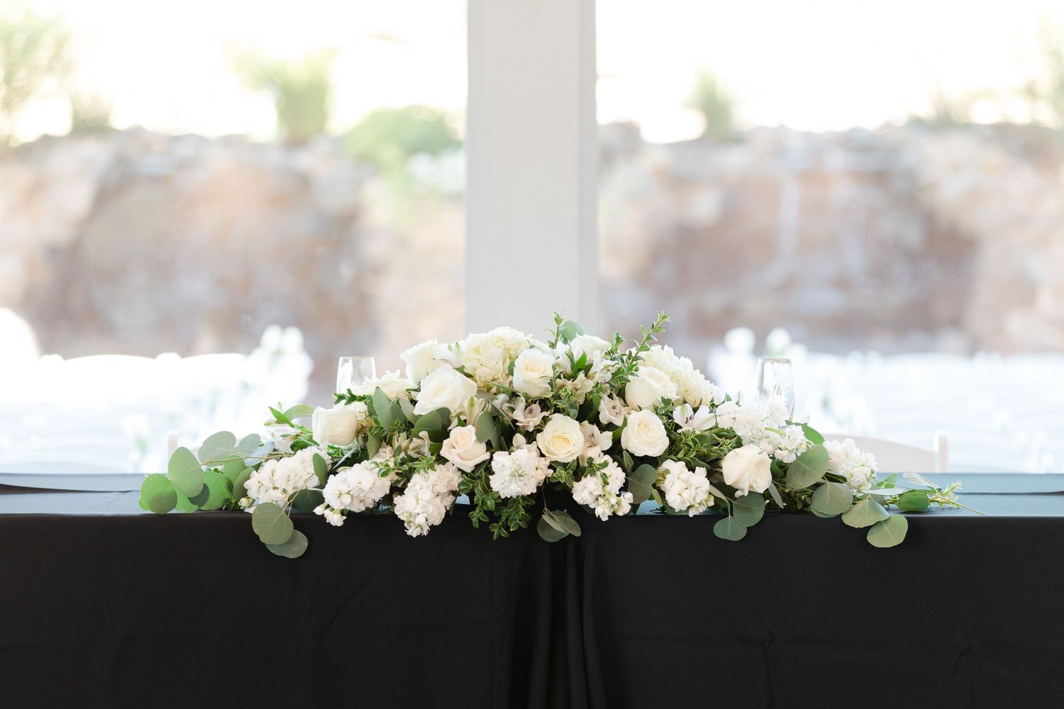 White floral garland with roses and greenery decorates the top edge of a window frame.