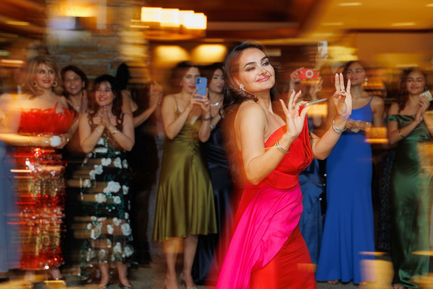 People dancing and celebrating at a wedding reception in a warmly lit ballroom with festive atmosphere.