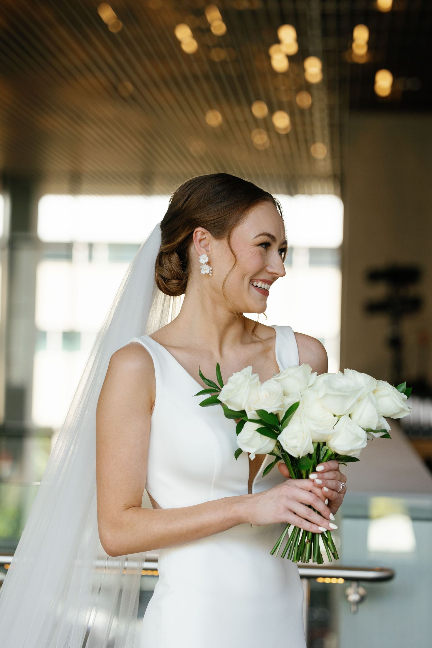 A bride in a white wedding dress holds a classic bouquet of white roses during her wedding celebration.