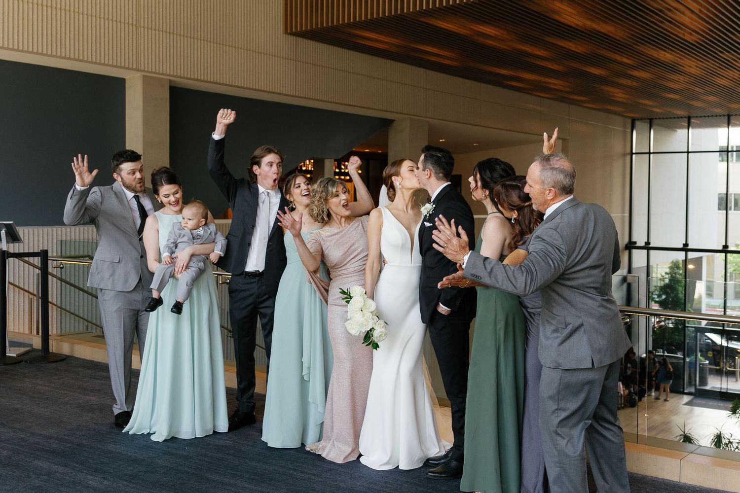 Wedding party members share emotional reactions during a first look reveal moment in an elegant indoor venue.