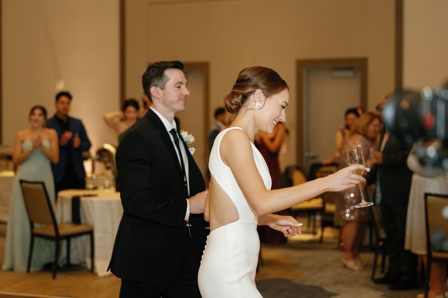 Bride and groom share their first dance at an elegant wedding reception with guests watching from their tables.