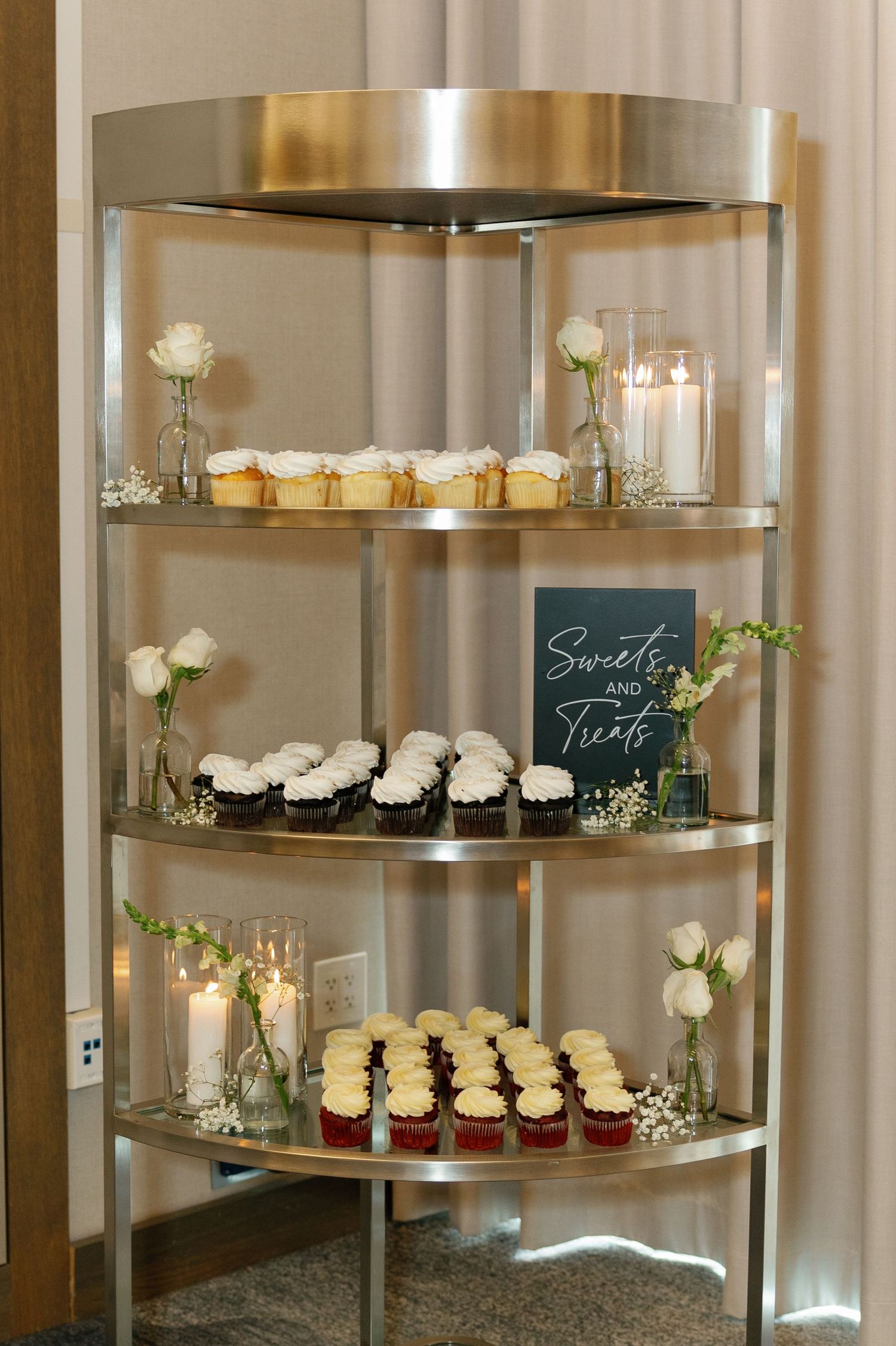 Modern round wall-mounted display shelves with cupcakes and white roses create an elegant dessert presentation.