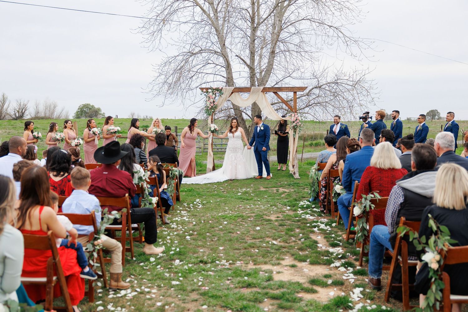 Large group of people gathered outdoors for a spring event with trees and buildings in the background.