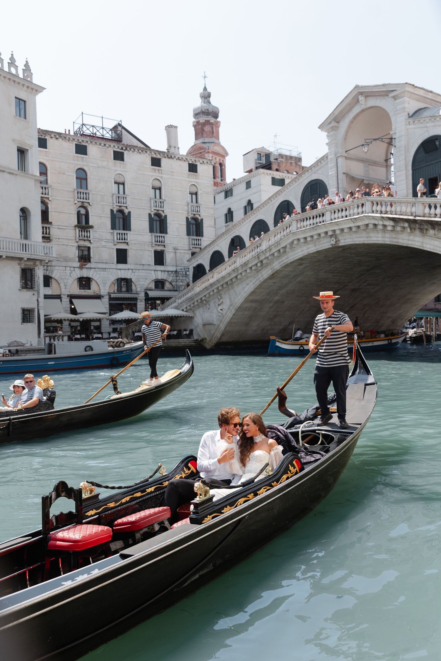 Romantic gondola rides along Venice's Grand Canal near the iconic Rialto Bridge with traditional striped-shirt gondoliers.