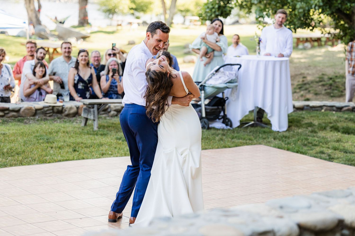 Wedding guests dance and celebrate outdoors during a joyful reception on a sunny summer day.