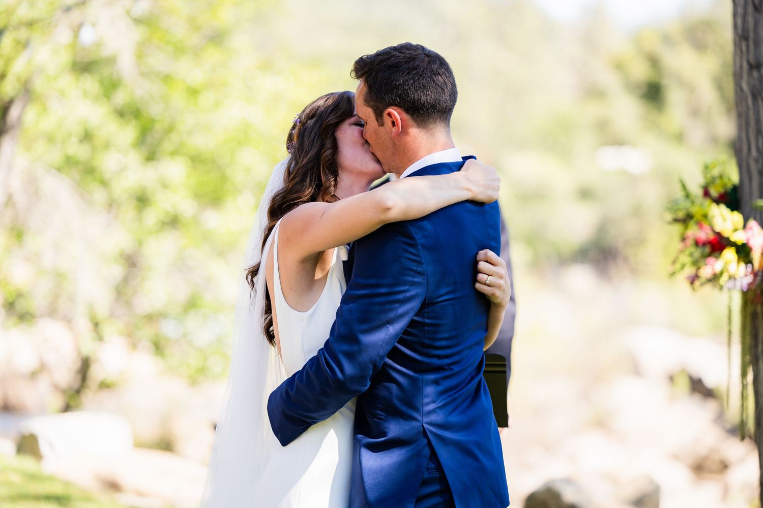 Couple in navy blue and white outfits embracing outdoors during a romantic photoshoot in natural lighting.