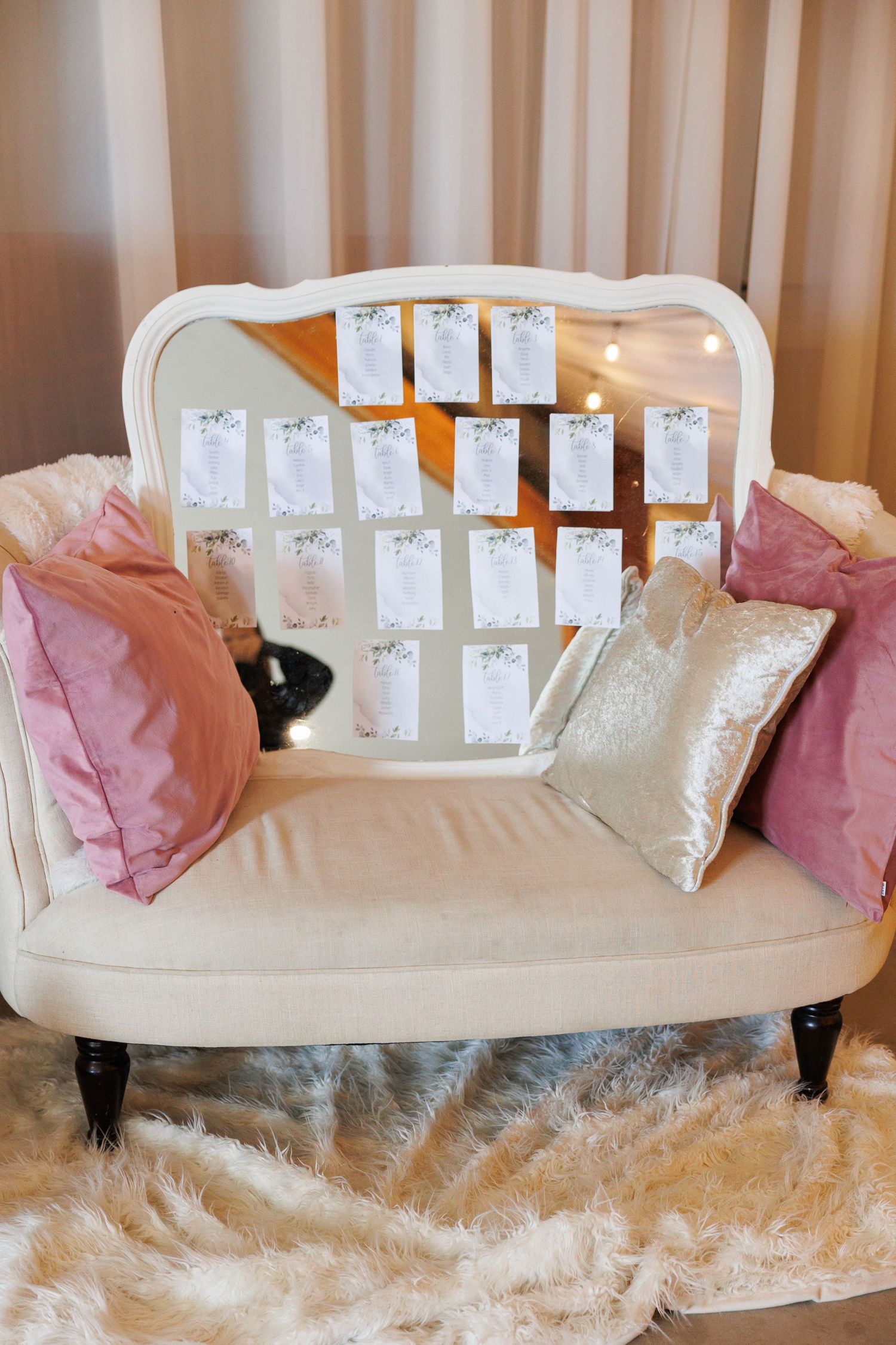 White Victorian style chaise lounge sofa with pink and silver accent pillows on fluffy white faux fur rug.