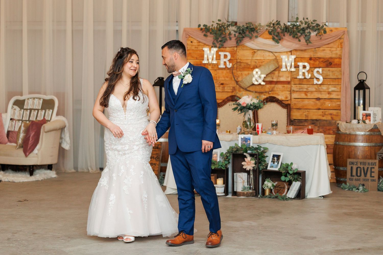 A wedding reception venue decorated with rustic wooden accents and floral arrangements features a romantic dance scene.