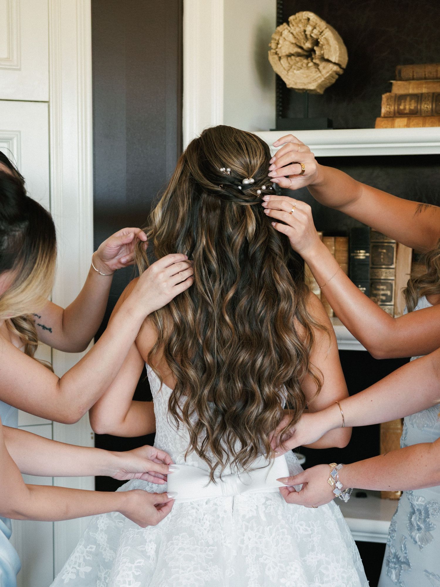 A series of photos showing the back of a white wedding dress being laced up and adjusted.