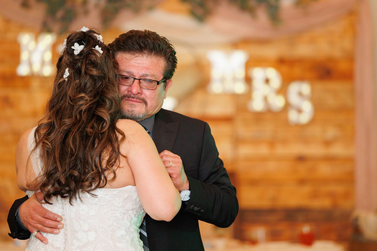 A couple shares a romantic dance moment at a rustic wooden-walled wedding reception venue.