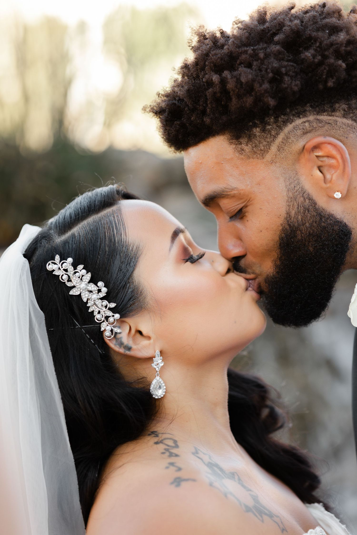 A romantic wedding portrait of a couple sharing an intimate moment, with the bride wearing a crystal hair accessory and veil.