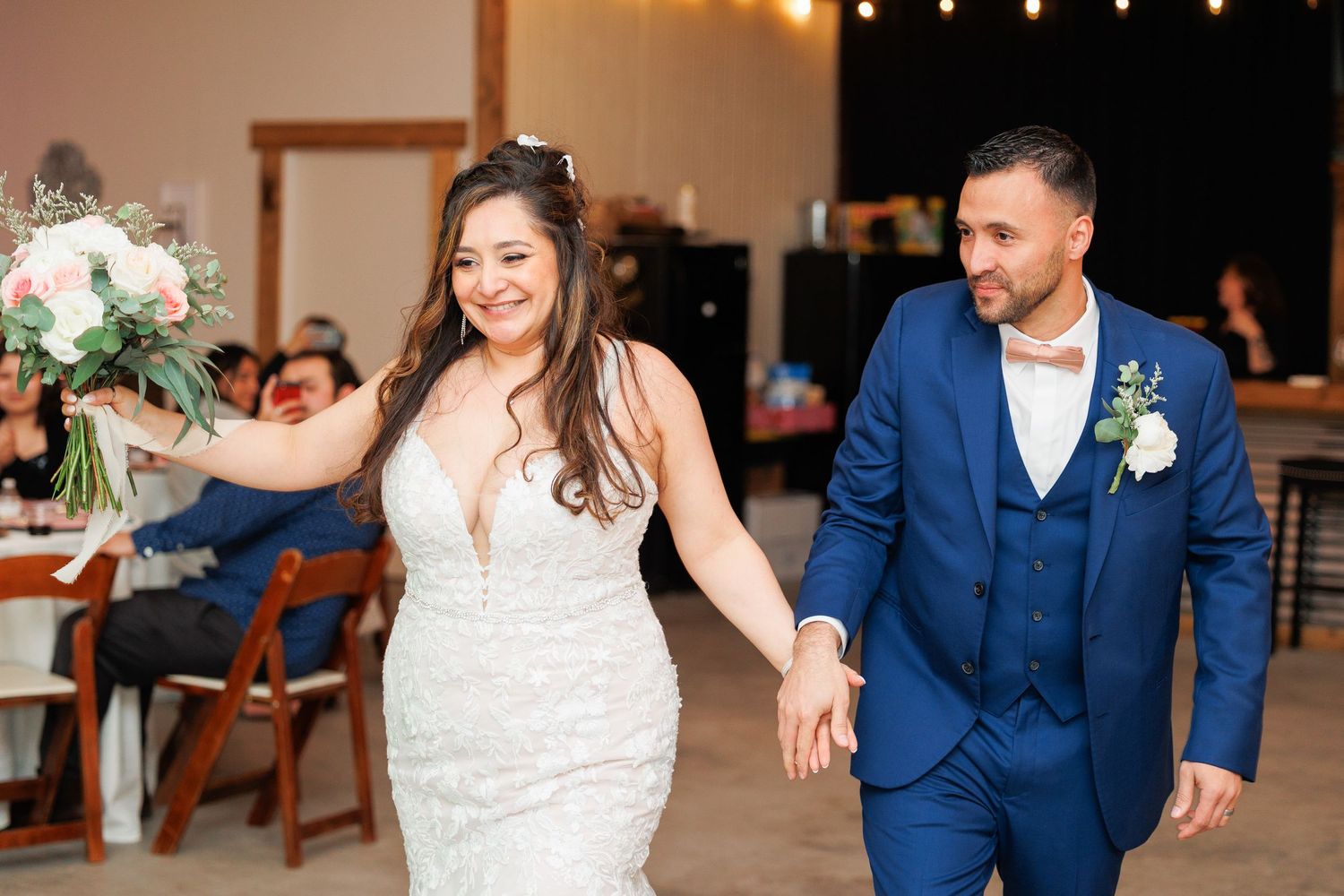 A bride and groom dance together at their wedding reception in a warmly lit venue.