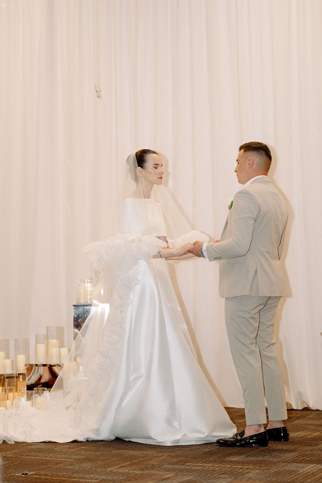 A wedding first look sequence with a couple dancing against a white backdrop with glowing candles.
