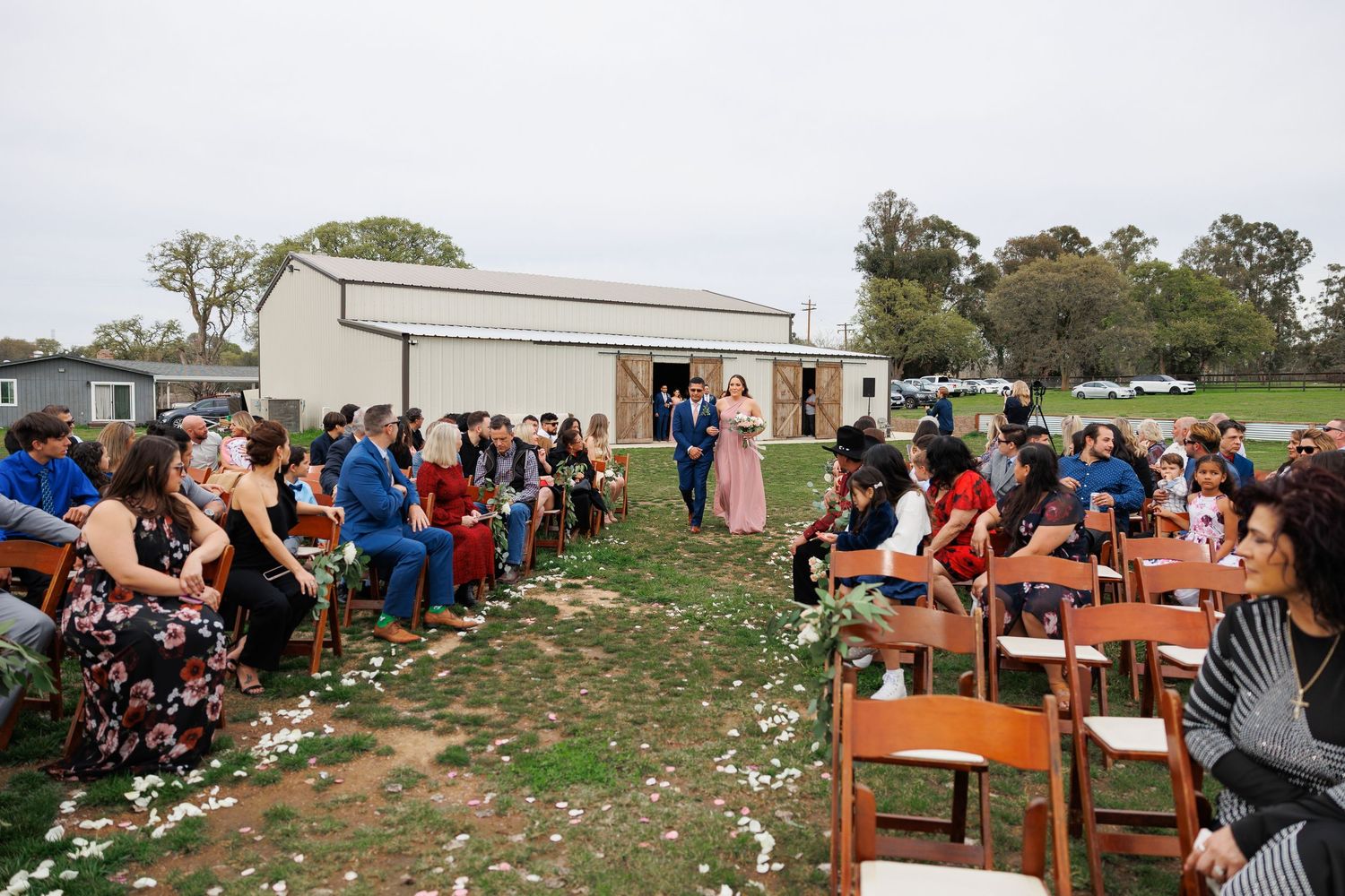 Outdoor wedding ceremony setup with wooden chairs arranged in rows on a grassy hillside overlooking the landscape.
