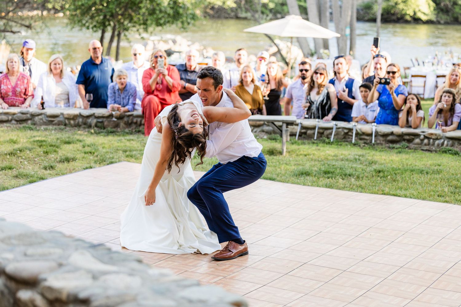 Wedding guests dance together on an outdoor patio during a celebration at sunset.