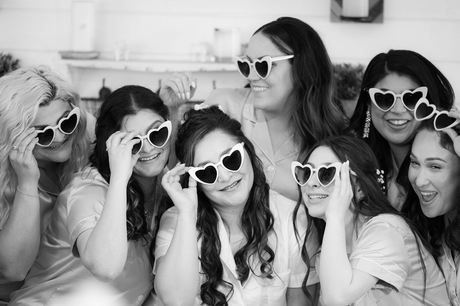 A group of people wearing white sunglasses pose together in a black and white photo collage.