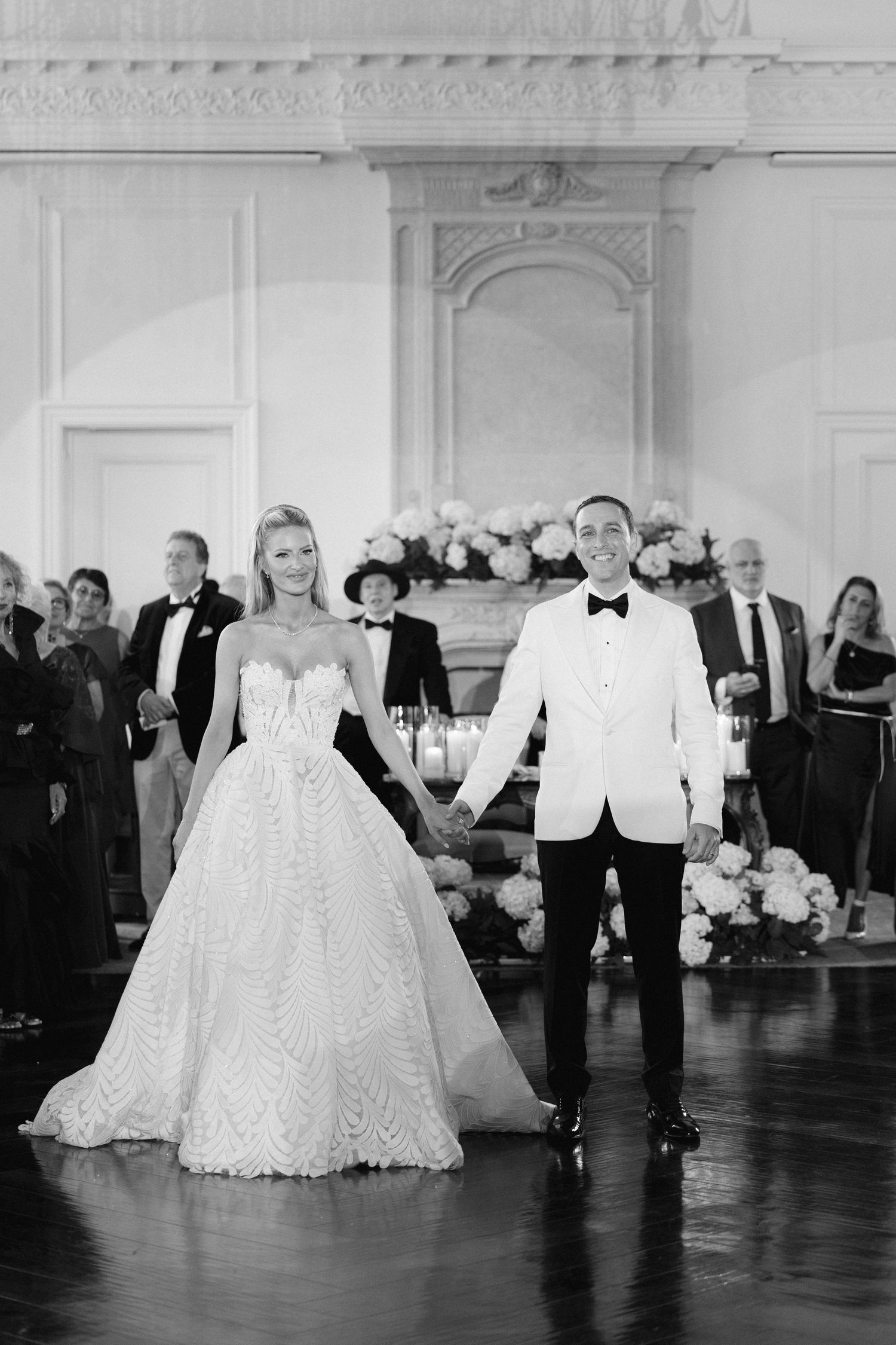 Black and white photo series showing a couple's first dance at an elegant wedding reception in a grand ballroom.