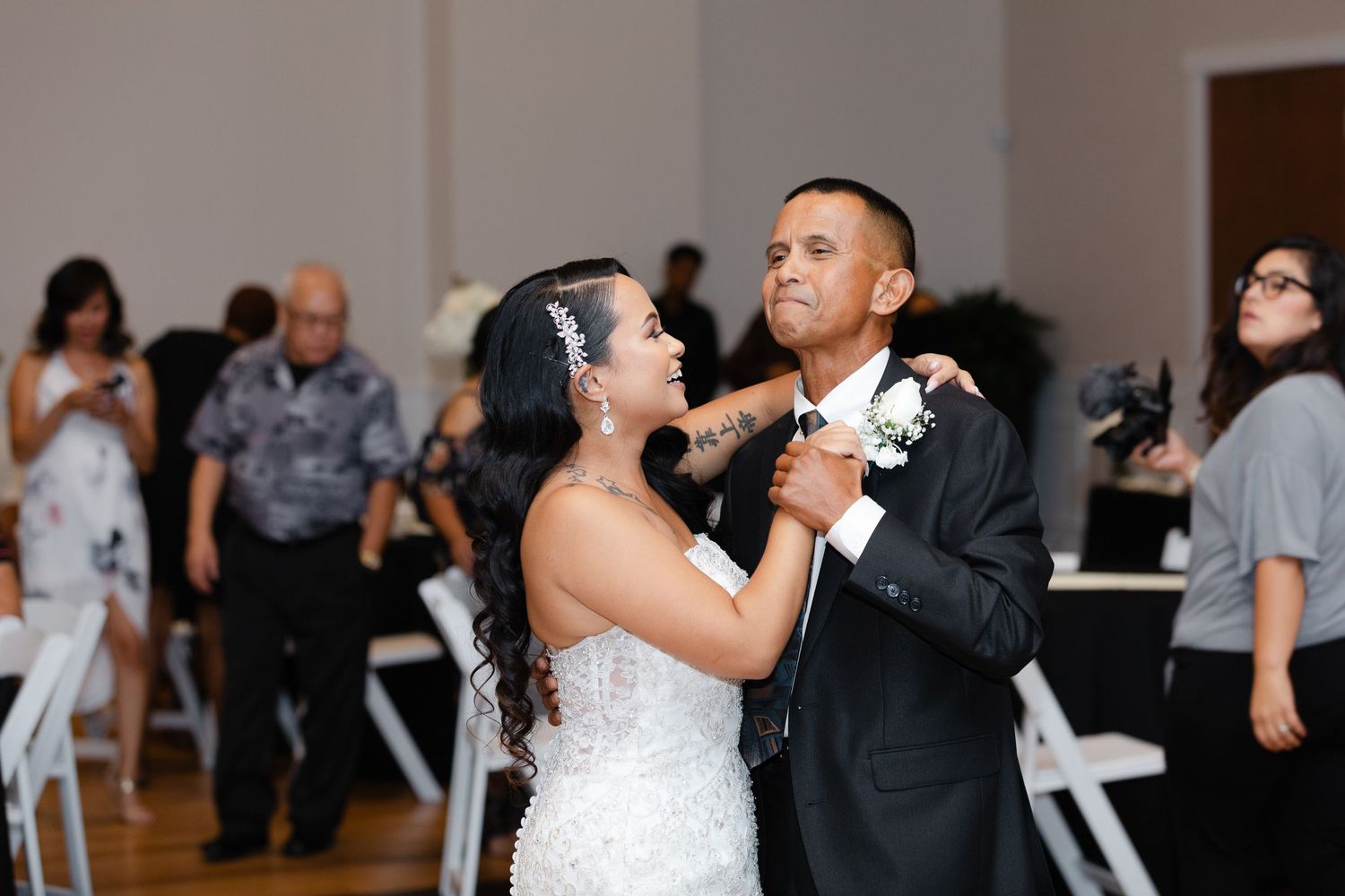 A couple in formal wedding attire share a romantic dance together at their wedding reception.