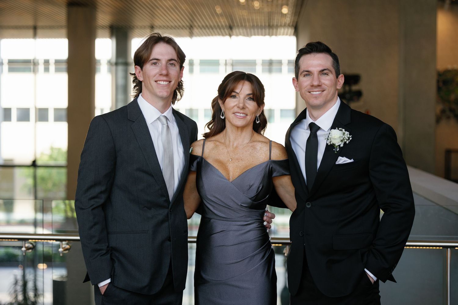 Wedding party members in formal attire pose together in an elegant indoor venue.