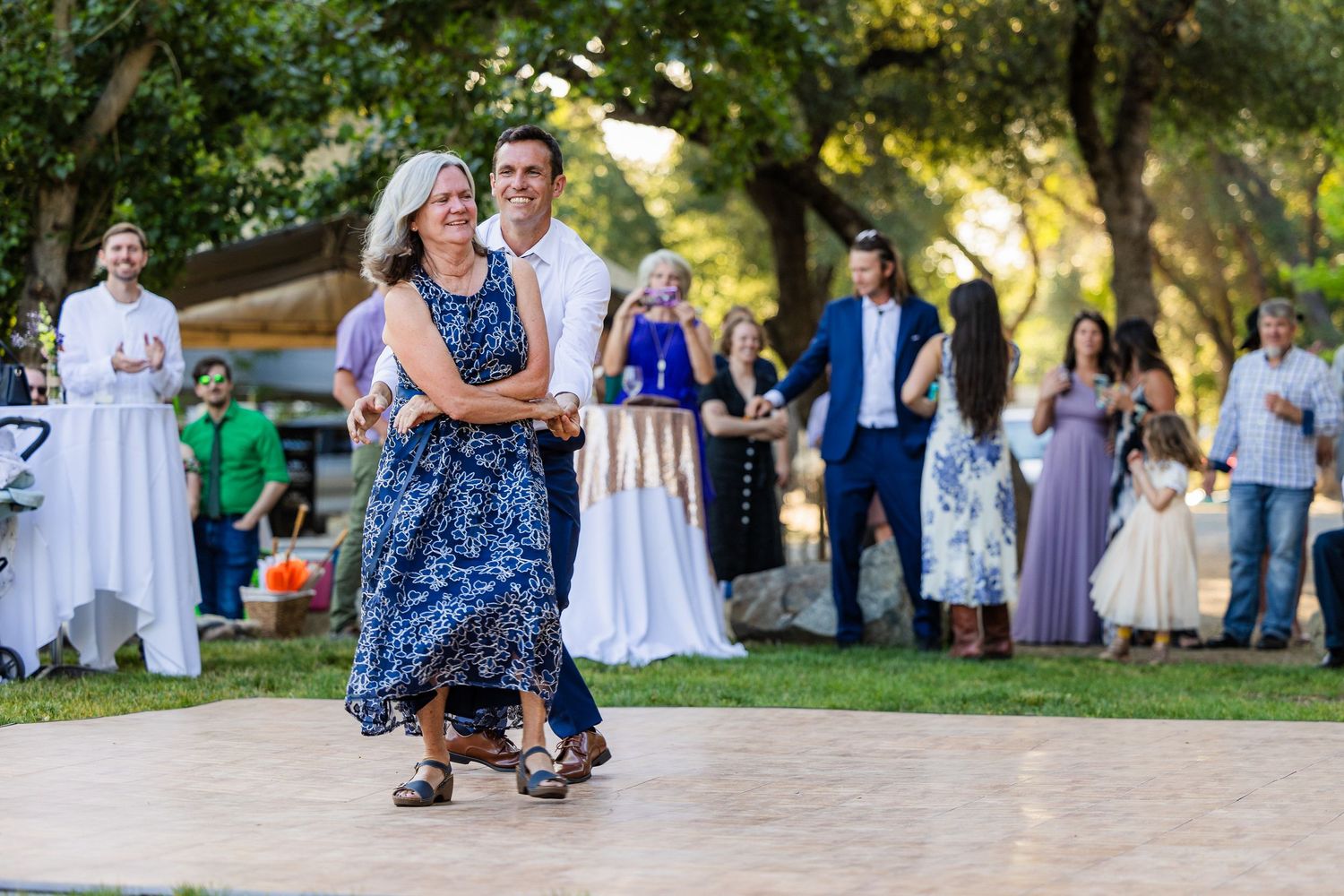Couples dance together on an outdoor patio during a summer wedding reception celebration.
