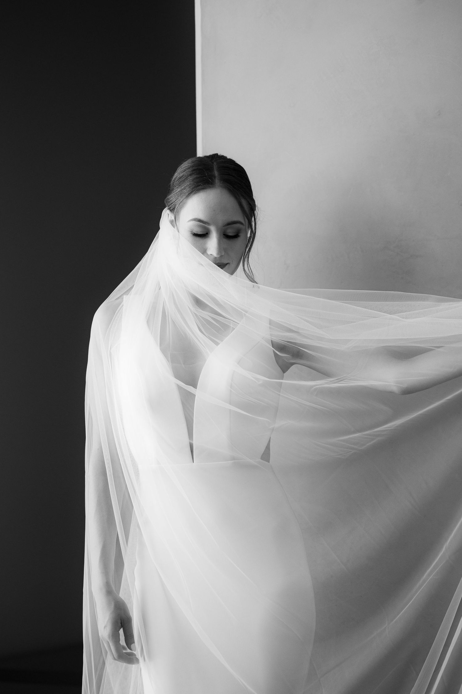 Ethereal black and white bridal portrait with flowing veil creating a dreamy, romantic atmosphere.