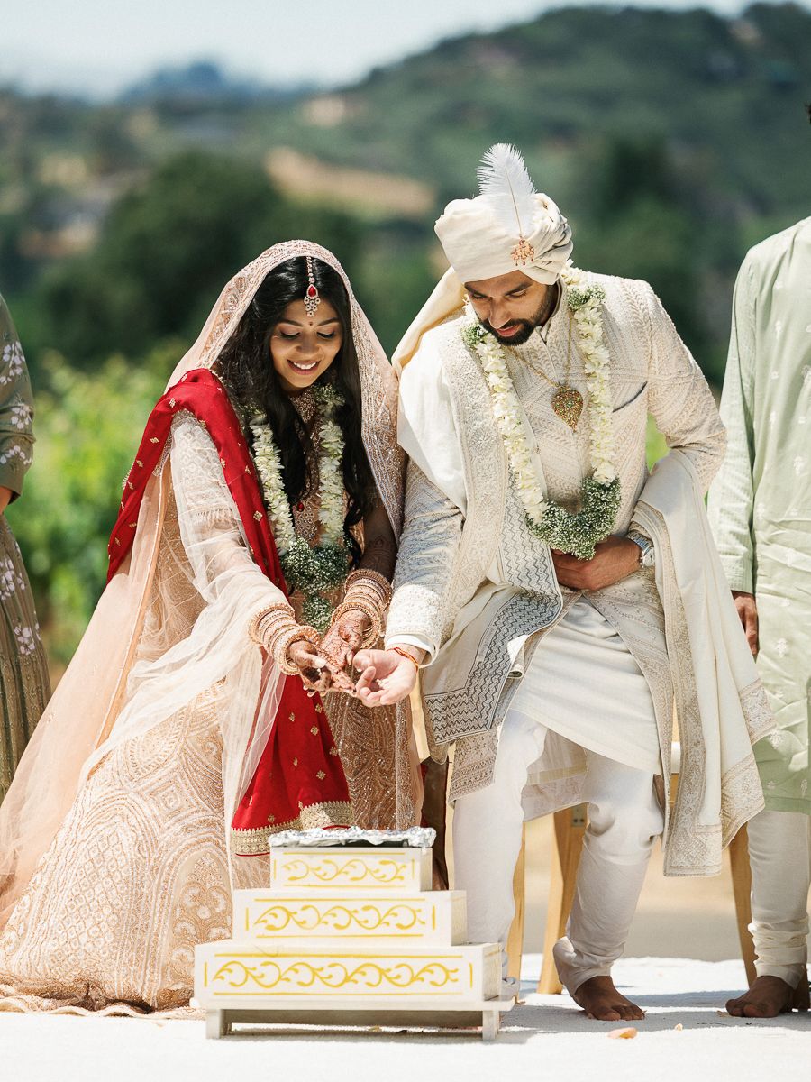 Wedding couple and guests sign traditional documents during an outdoor ceremony with scenic mountain views in background.