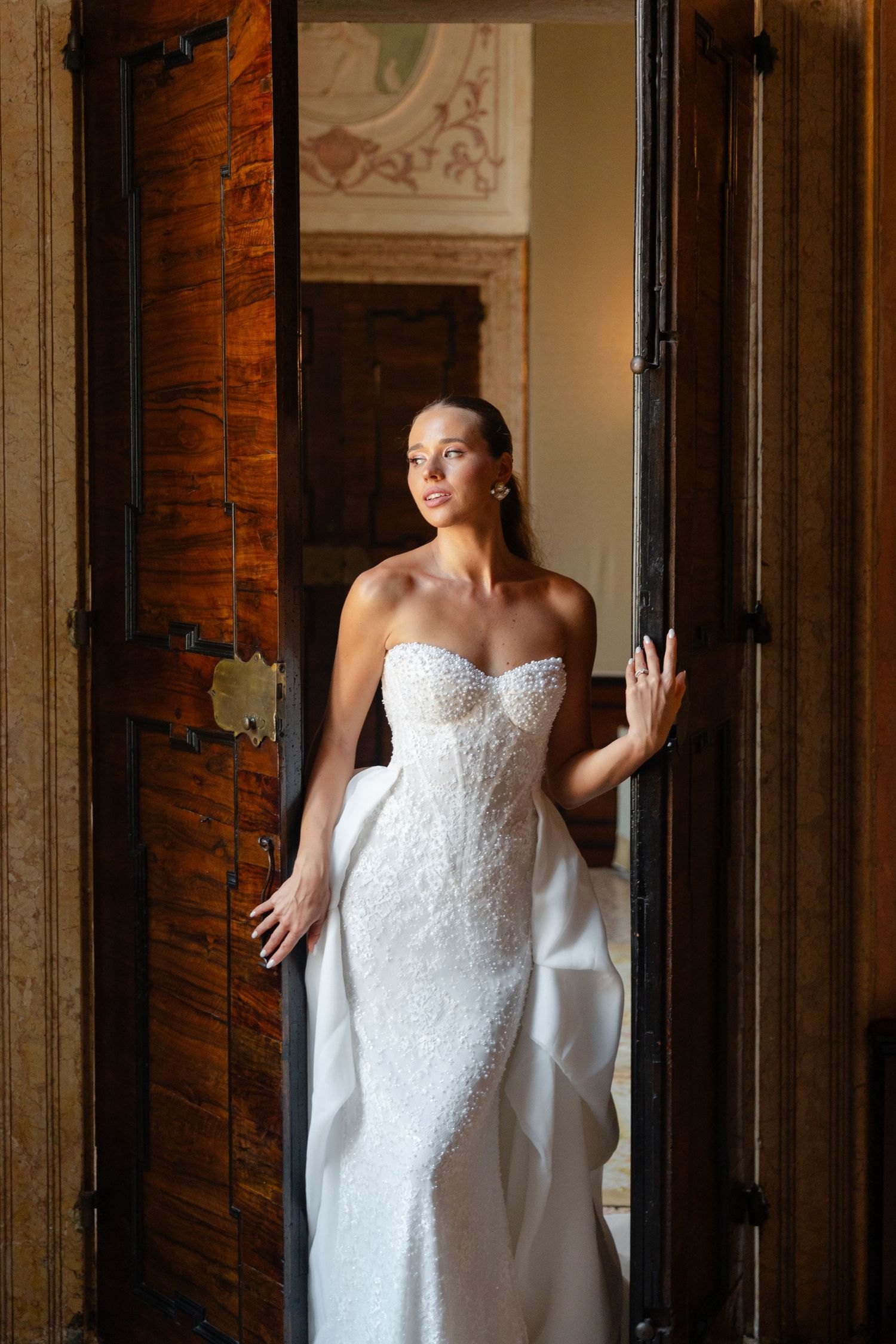 Four sequential photos show a bride in a white lace strapless wedding dress posing against a rustic wooden wall.