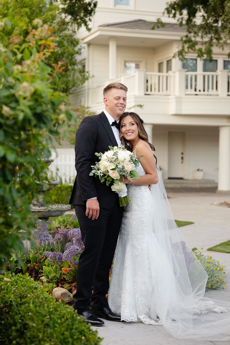Romantic wedding couple portraits in a garden setting with white flowers.