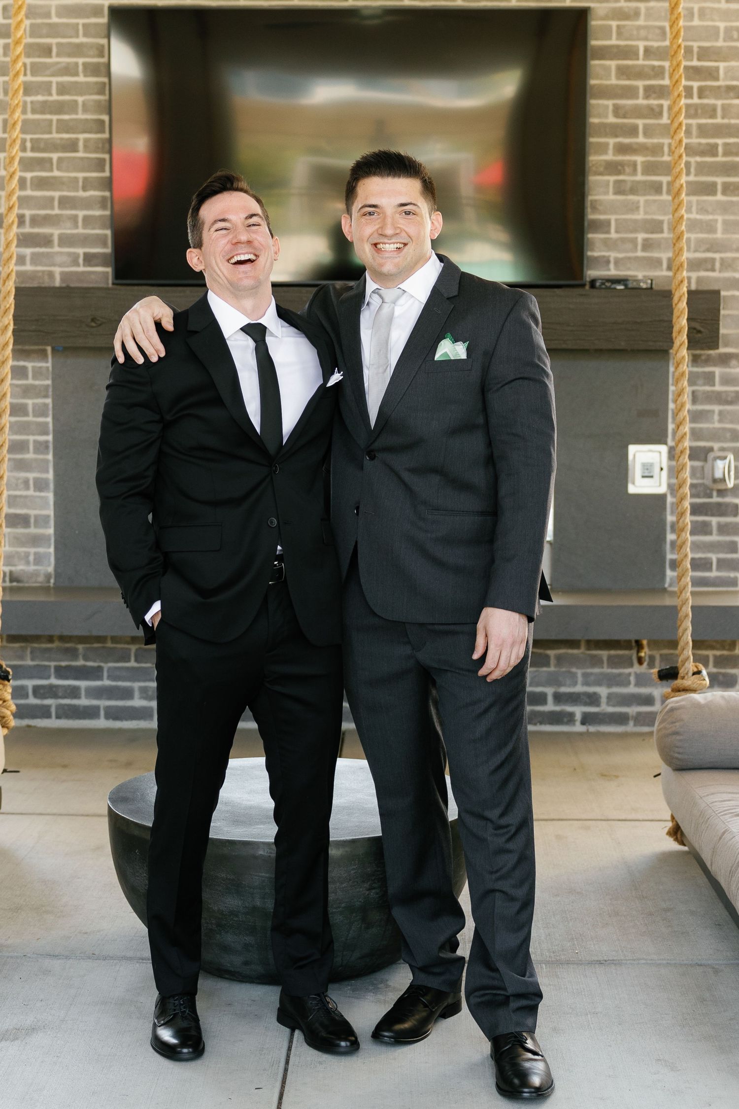 Four groomsmen in black suits and ties pose together on a porch in a series of candid wedding party photos.