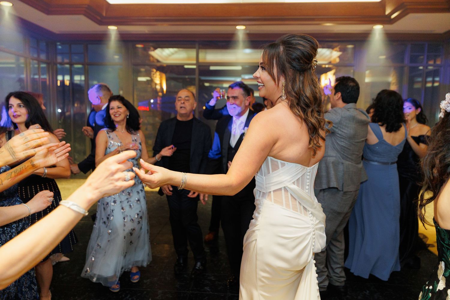 People dancing and celebrating at an elegant wedding reception with blue lighting and formal attire.