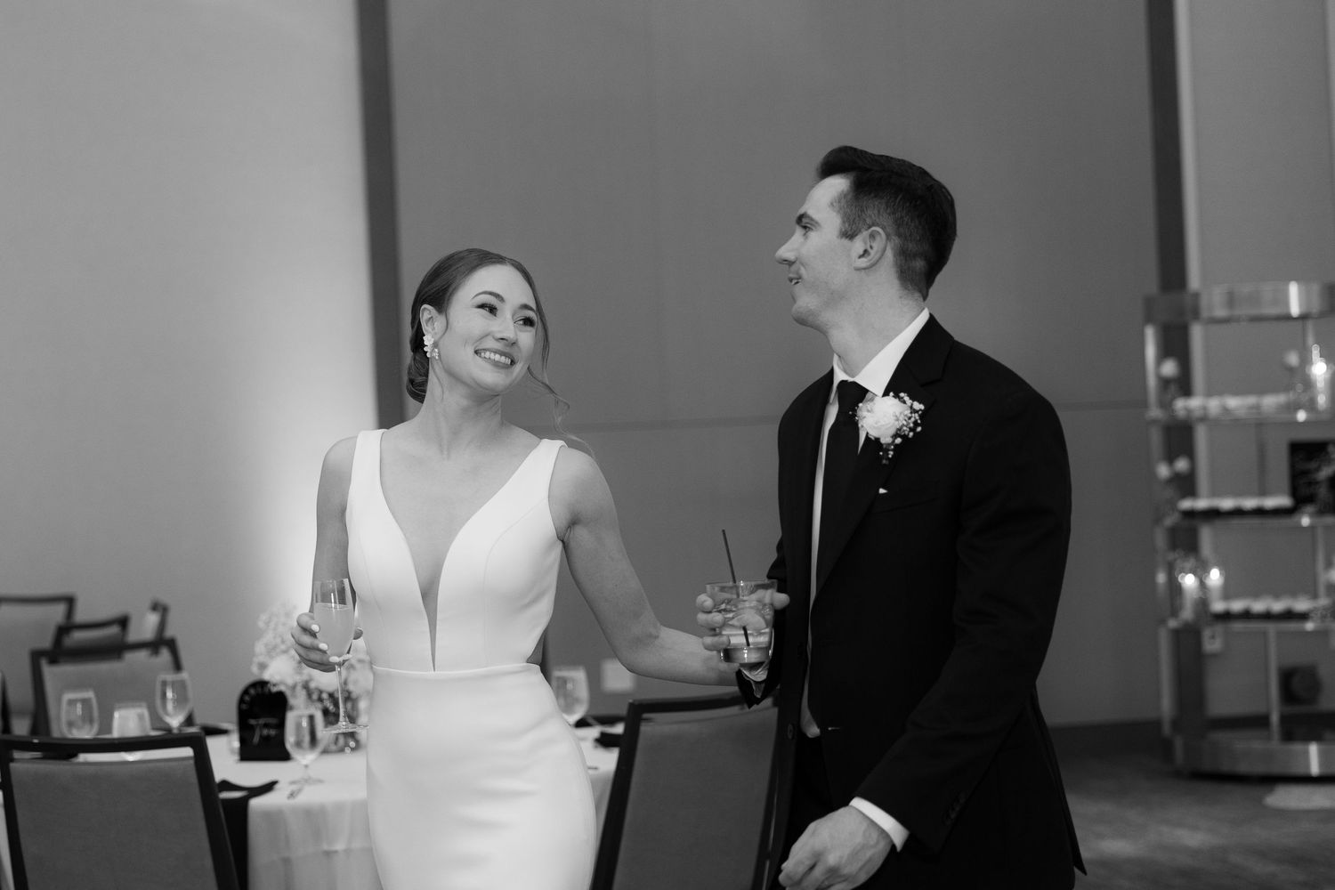A couple shares a joyful moment together at their wedding reception while holding champagne glasses.