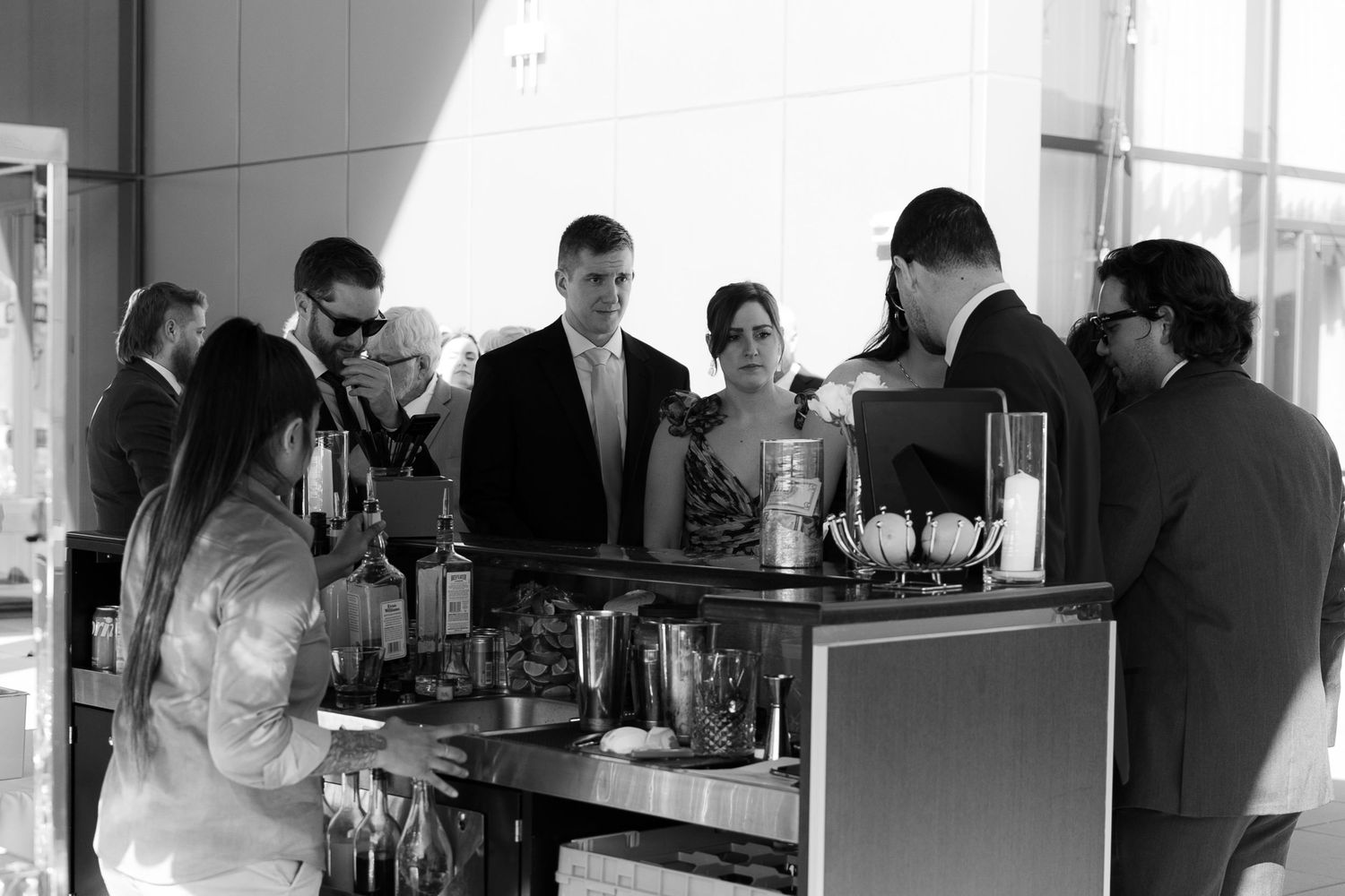 People gathered around a counter at a coffee bar preparing drinks and working in a modern cafe setting.