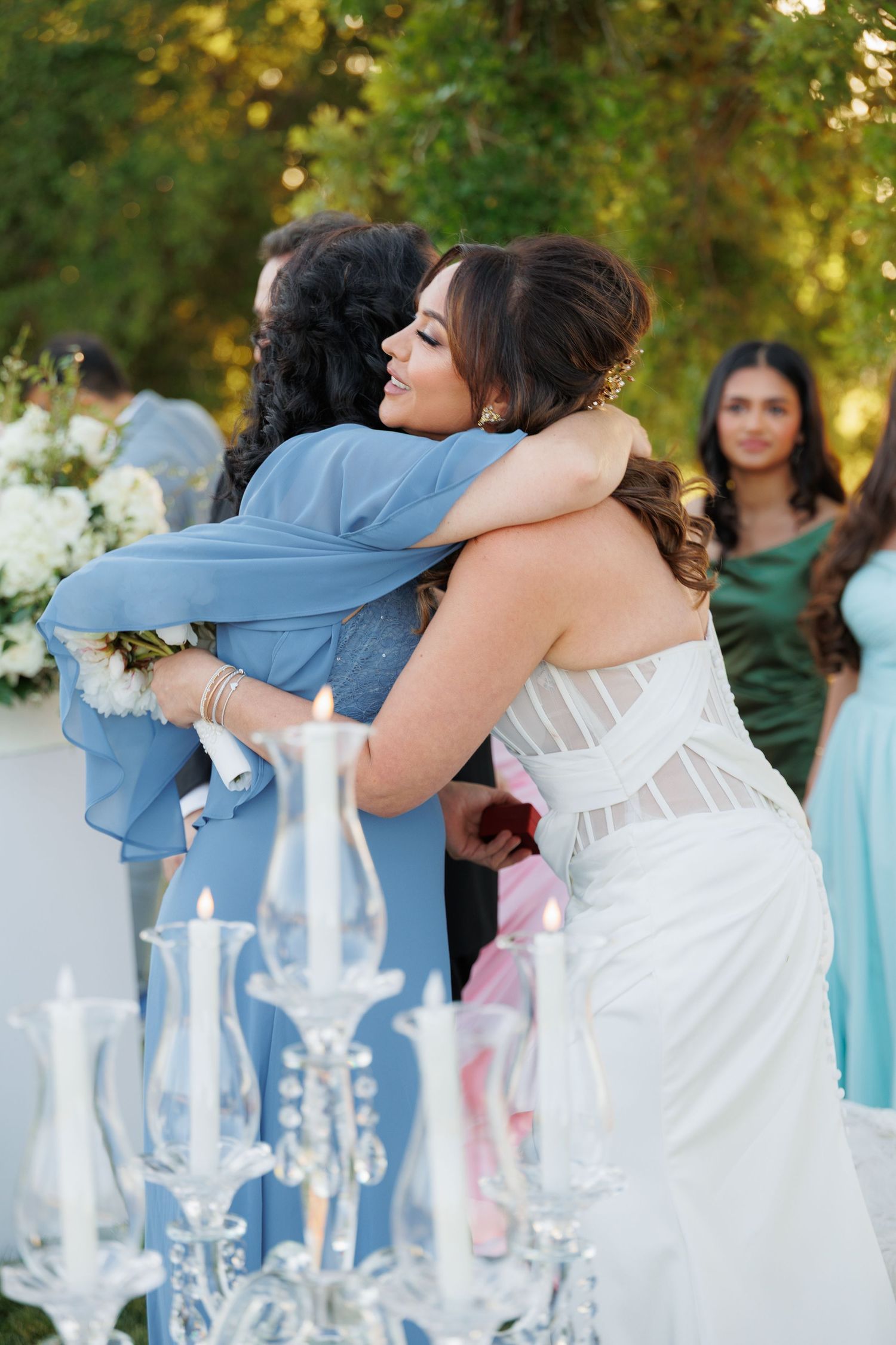 A tender embrace at an elegant wedding reception with decorative candelabras and floral arrangements in the foreground.
