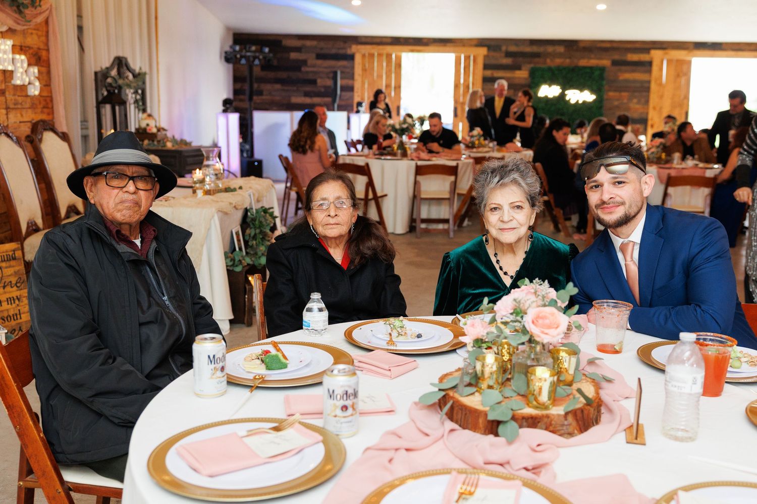 A panoramic view of people seated at long tables in a rustic dining room during a social gathering.