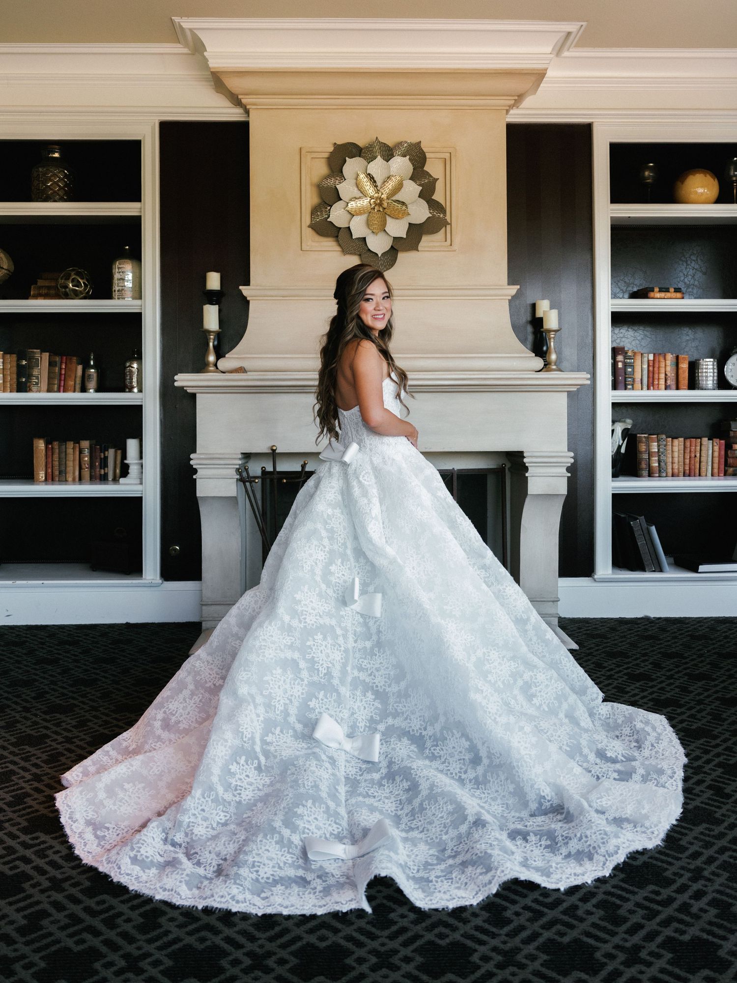A flowing white lace wedding dress is showcased against built-in bookshelves in a sequence of elegant poses.