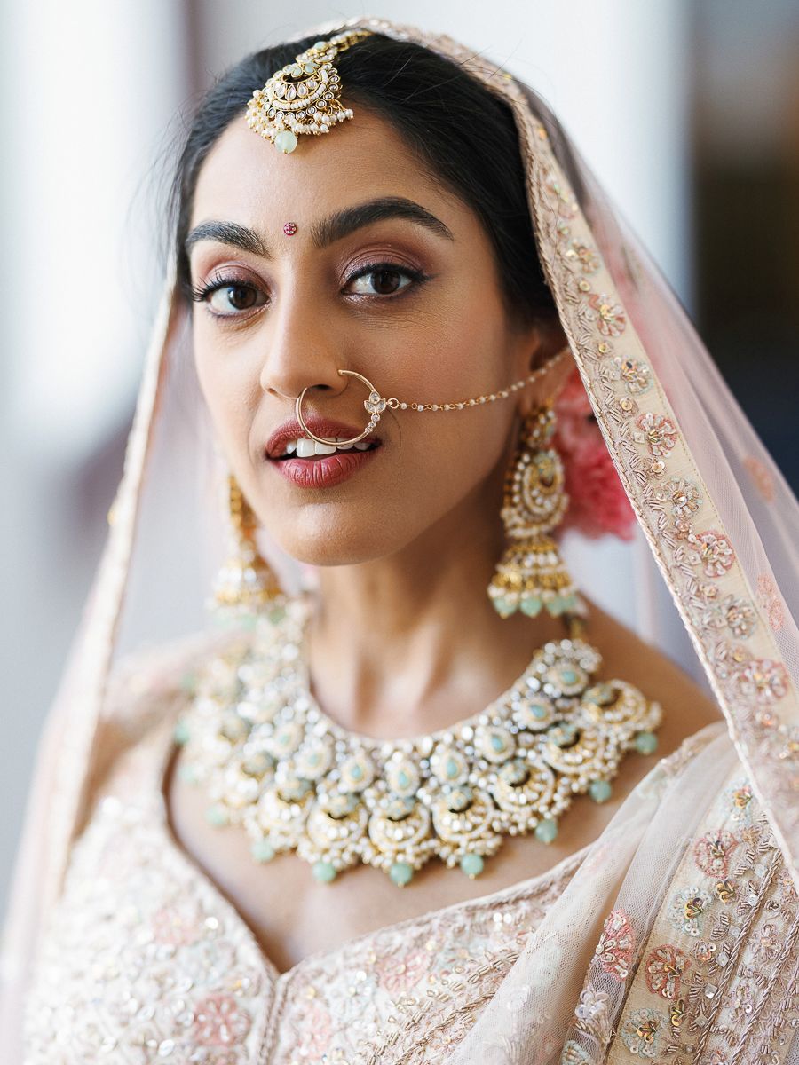 Detailed view of traditional South Asian bridal jewelry including necklace and nose ring.