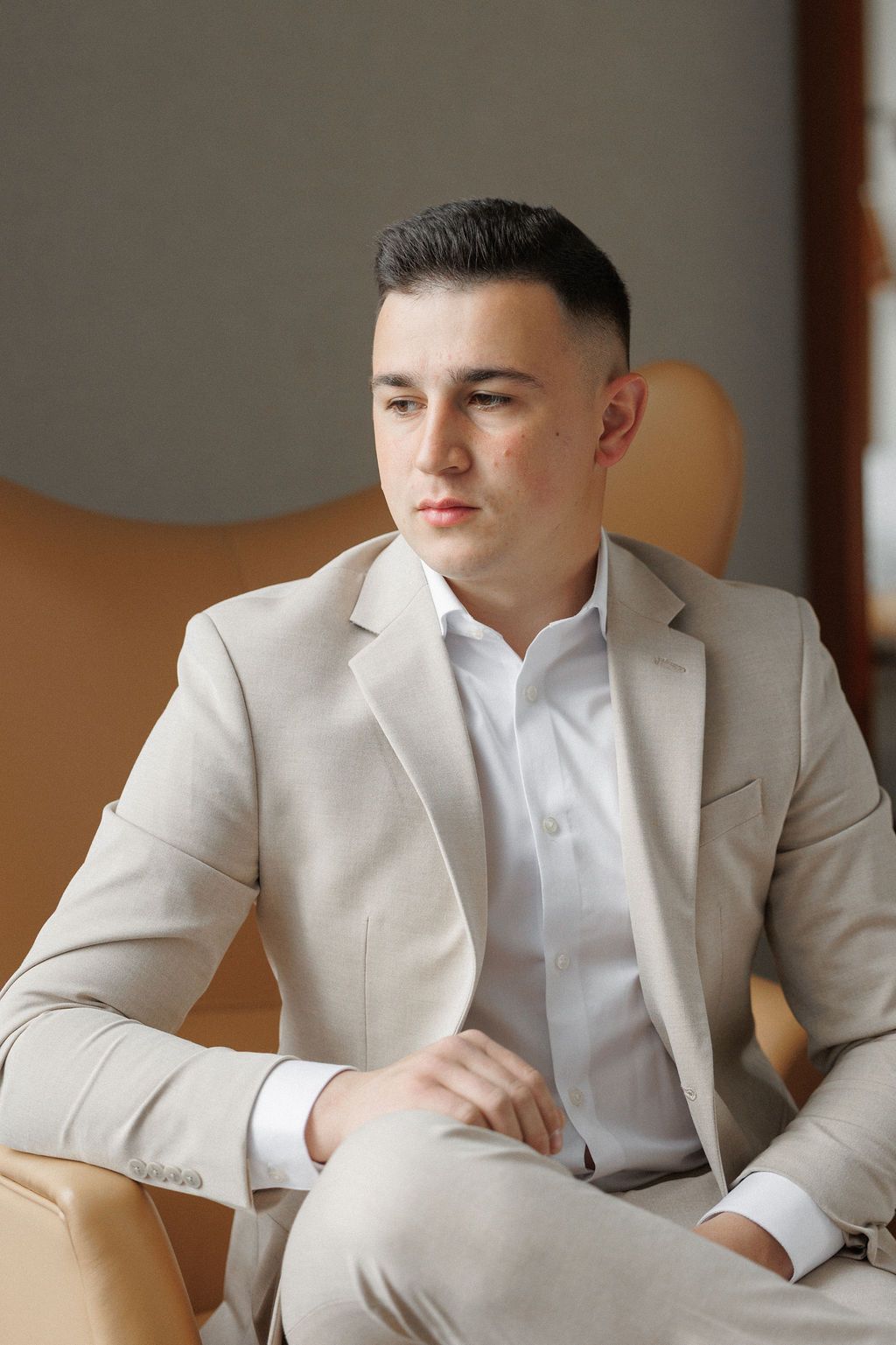 A series of photos showing a person in a light beige suit and white shirt sitting in an elegant interior setting.