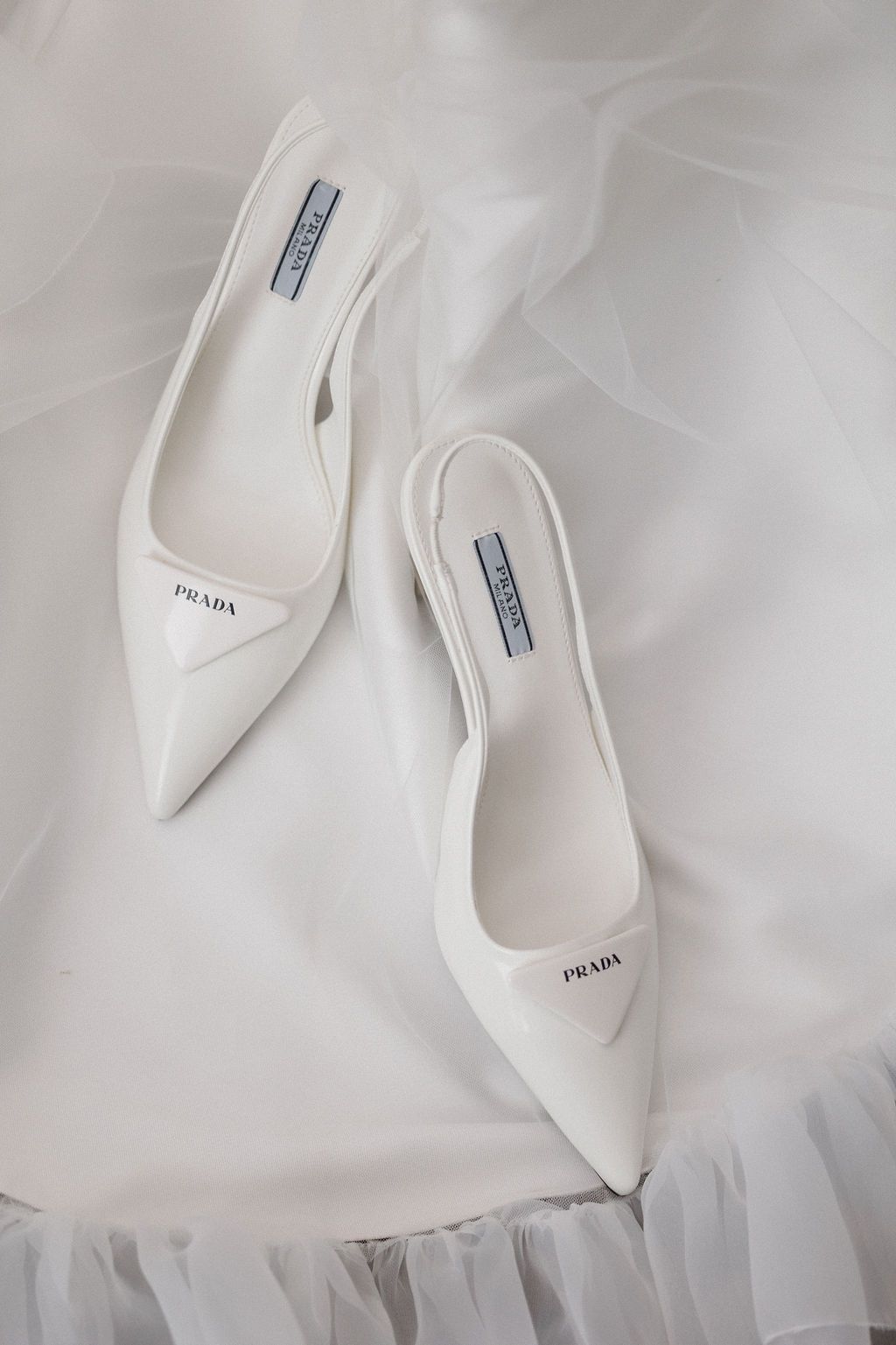 White Prada bridal shoes arranged on layers of delicate tulle fabric.