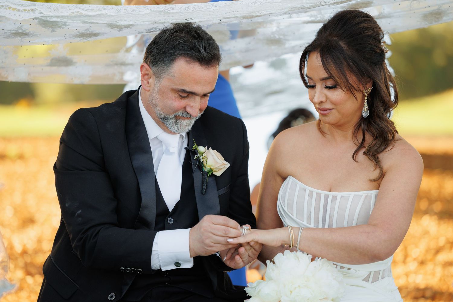 A romantic wedding couple shares intimate moments in an autumn setting with golden leaves and natural lighting.