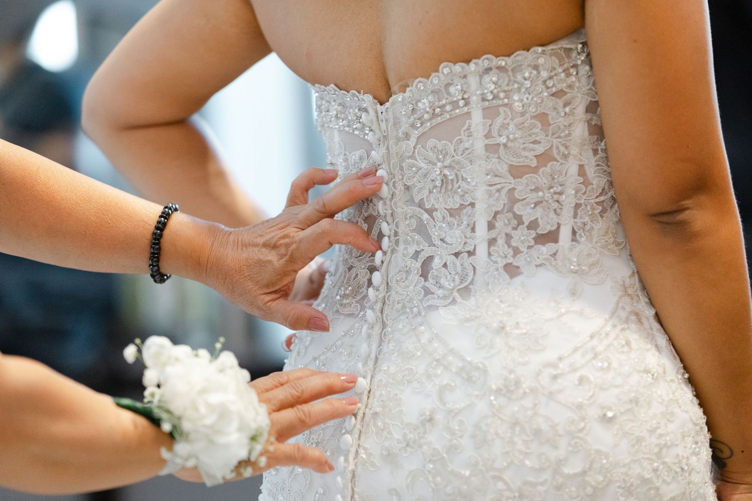 A bride in a detailed lace wedding dress holds a delicate white bouquet during the ceremony.
