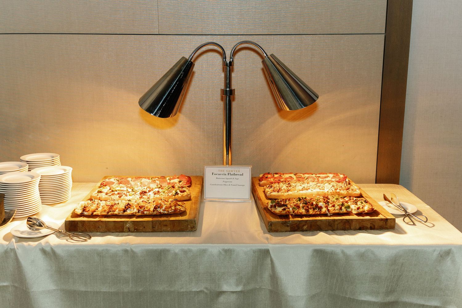 A collection of vintage desk lamps and lighting fixtures displayed on white shelves in a museum or gallery setting.