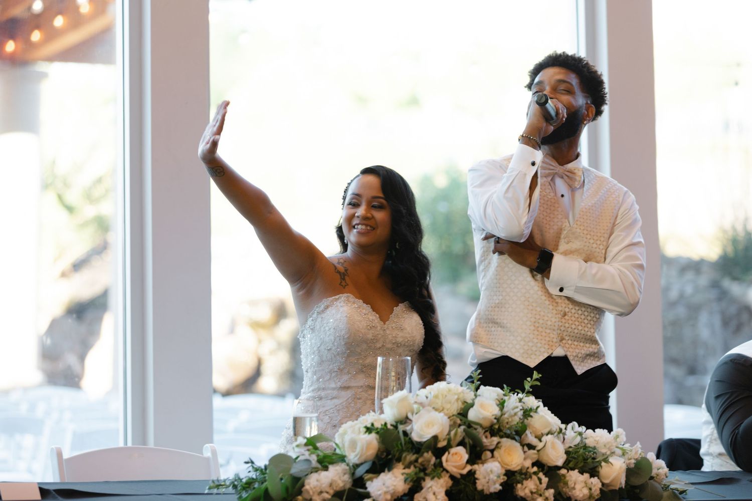 Wedding guests laugh and smile together during a joyful reception moment.