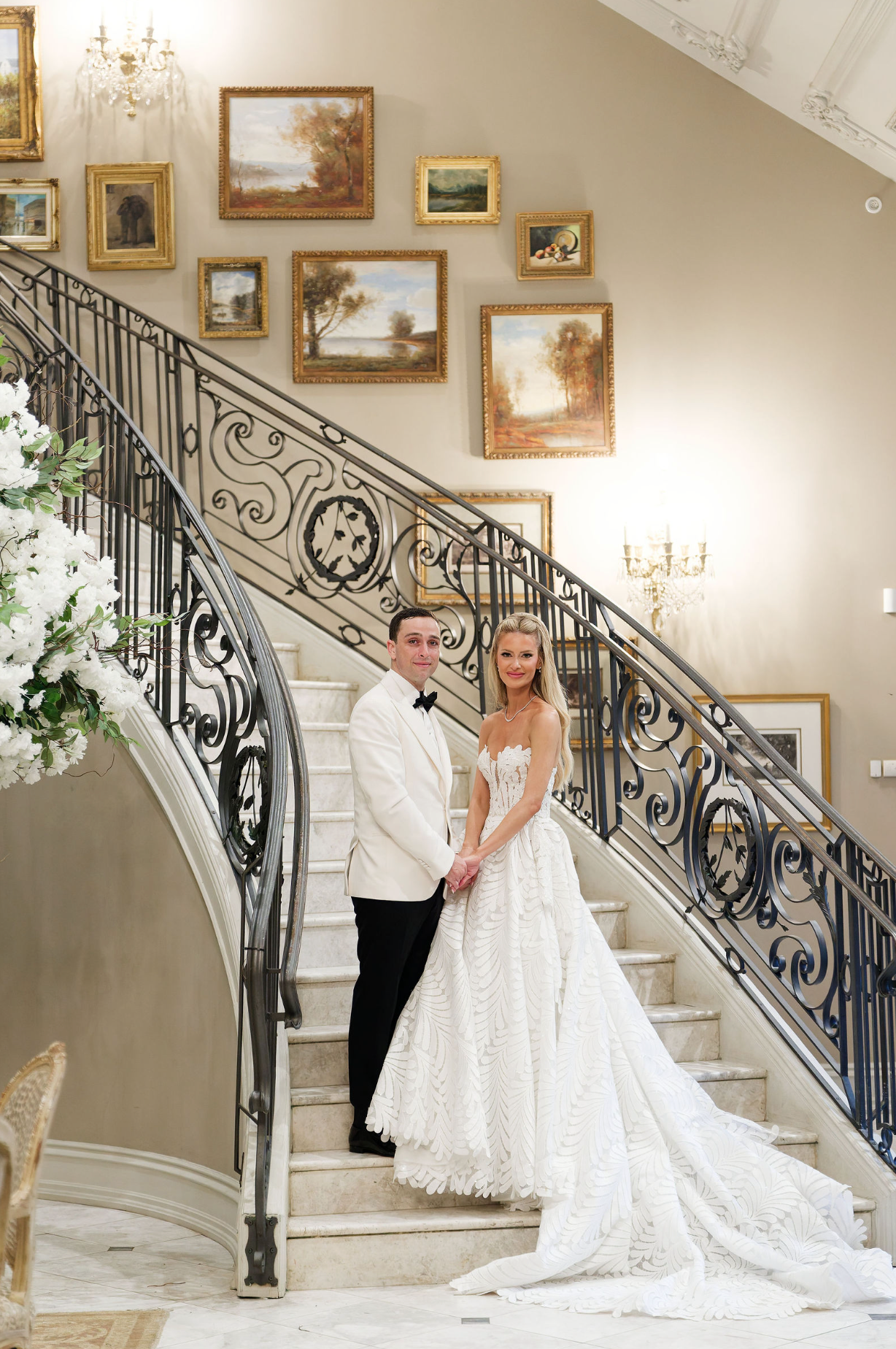 A series of elegant wedding photos on a grand staircase with ornate iron railings and framed artwork on cream walls.